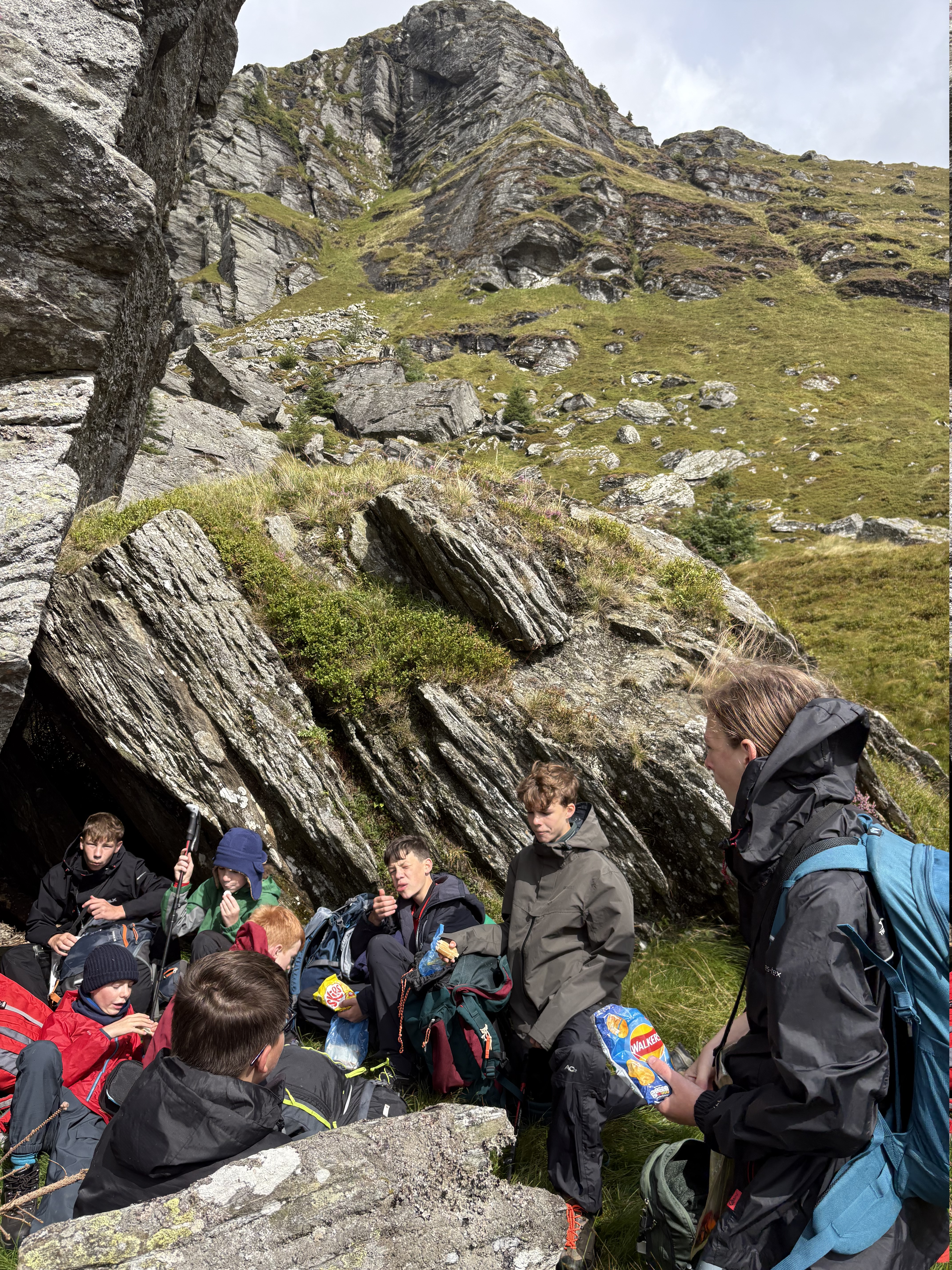 Scouts resting beside a mountain cave